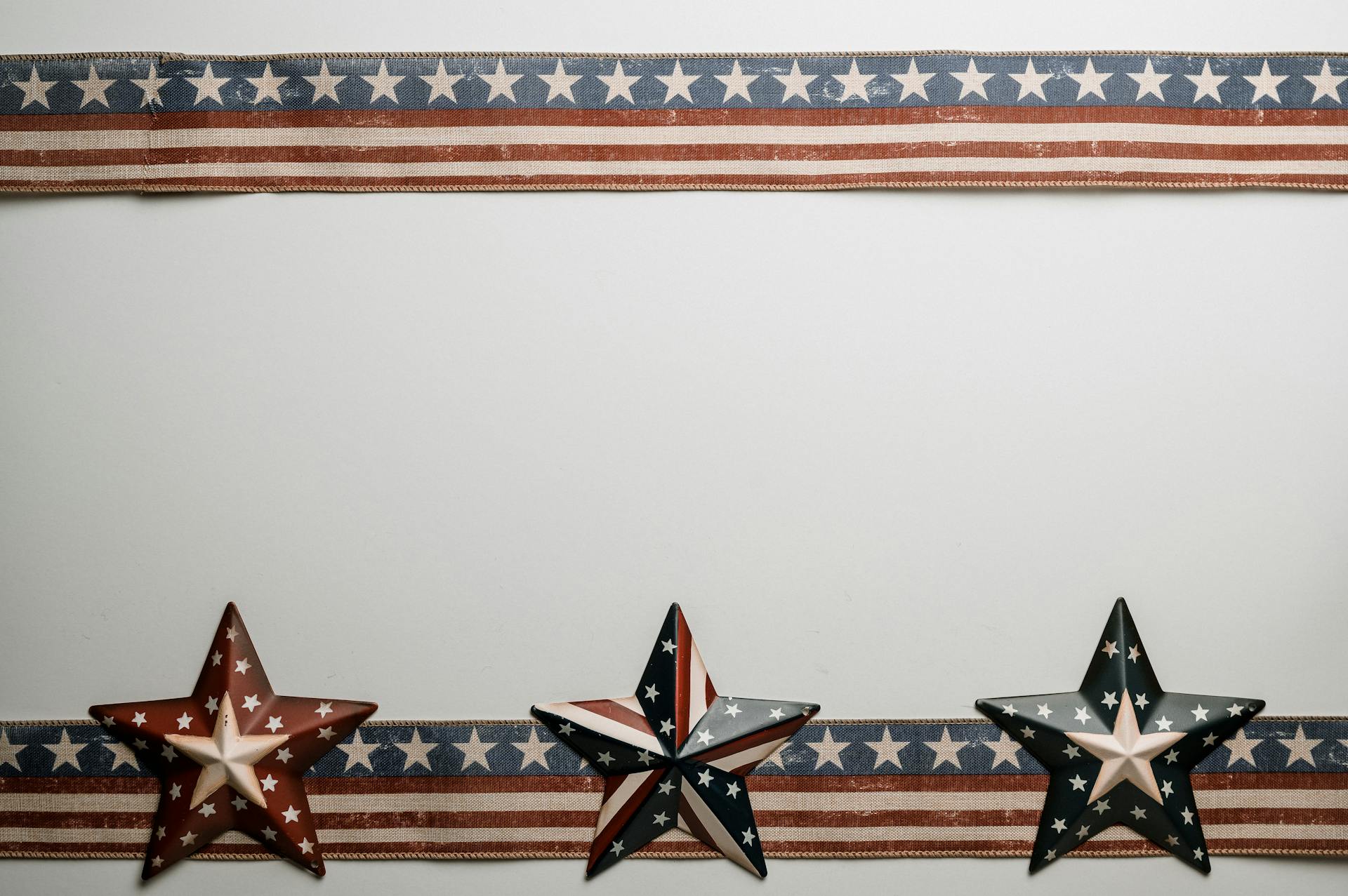 Star shaped souvenirs and ribbons with American flag pattern placed on white table