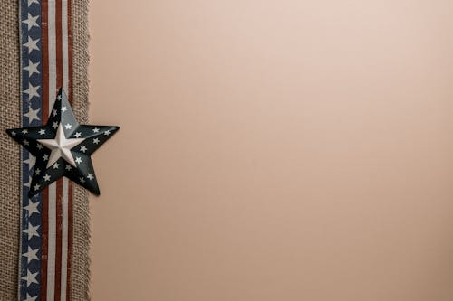 From above of star shaped badge placed on decorative ribbon with USA flag arranged on beige background