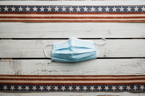 Free Top view of sterile face mask placed on white shabby wooden table with American flag ribbons Stock Photo