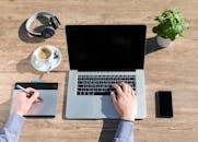 这个家庭办公工作空间时尚而实用，木桌上摆放着笔记本电脑、绘图平板电脑和一杯咖啡