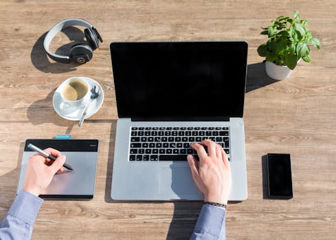 这个家庭办公工作空间时尚而实用，木桌上摆放着笔记本电脑、绘图平板电脑和一杯咖啡