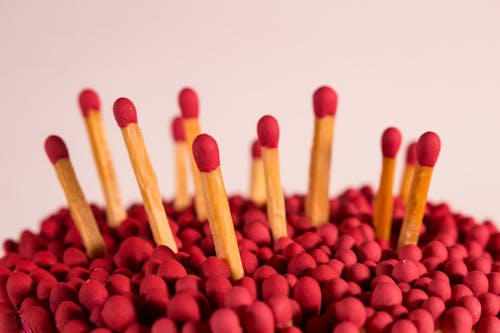 High angle of unused wooden matchsticks with red sulfured heads against white background