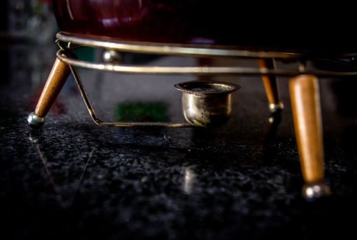 Detailed shot of a vintage fondue set on a dark granite surface, showcasing classic design.