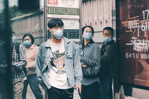 Free Group of adults wearing face masks standing on a Beijing street, capturing the city's urban life. Stock Photo