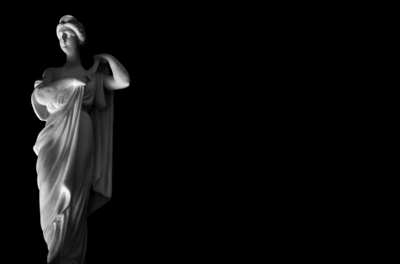 photo of a white marble statue on a black background with dramatic lig