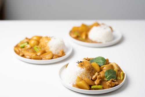 From above of served white table with portions of traditional Indian dish curry on ceramic plates