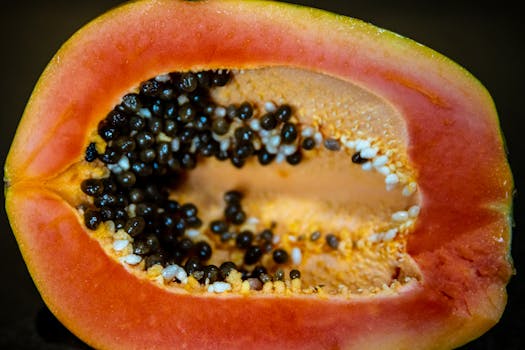 A vibrant close-up of a ripe papaya sliced in half, showcasing juicy seeds and fresh fruit.