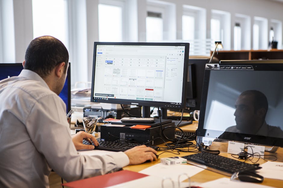 Man Operating Keyboard in Front of Monitor