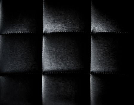 Detailed close-up of a black leather upholstery with a minimalist and modern texture.