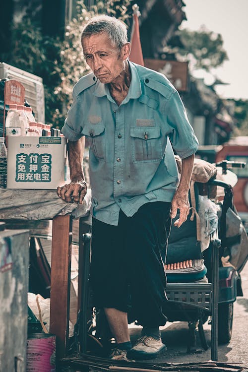 Elderly Man Standing Near a Stall