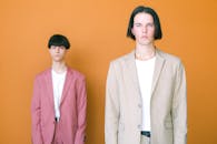 Woman in White Blazer Standing Beside Man in Pink Blazer