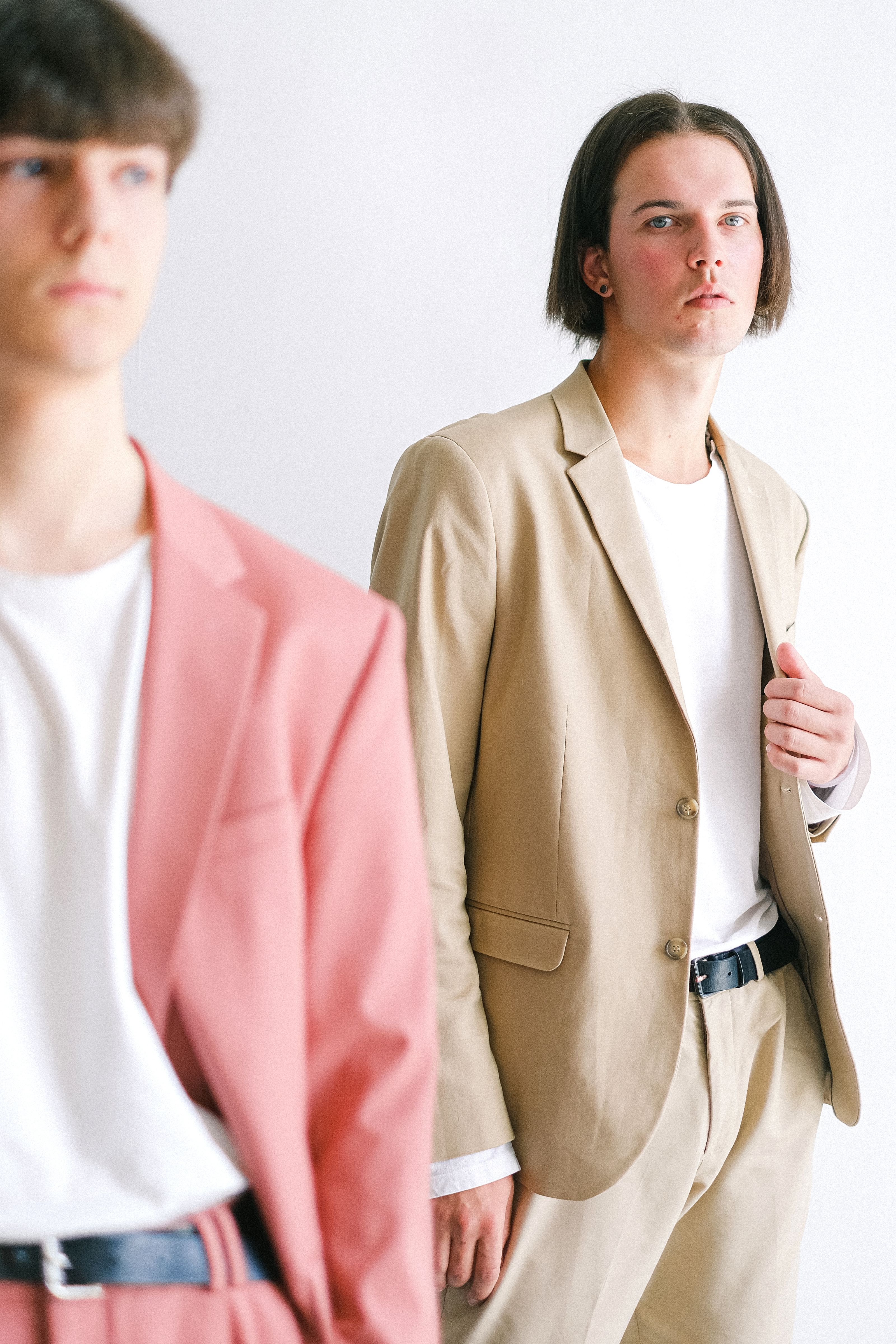 Retrato de jovens homens antenados à moda usando blazers em tons pastel posando em um estúdio.