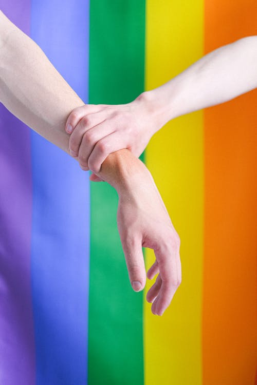 Free Arms in Front of a Gay Pride Flag Stock Photo