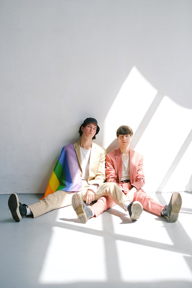 Two Men Sitting On The Floor With A Gay Pride Flag