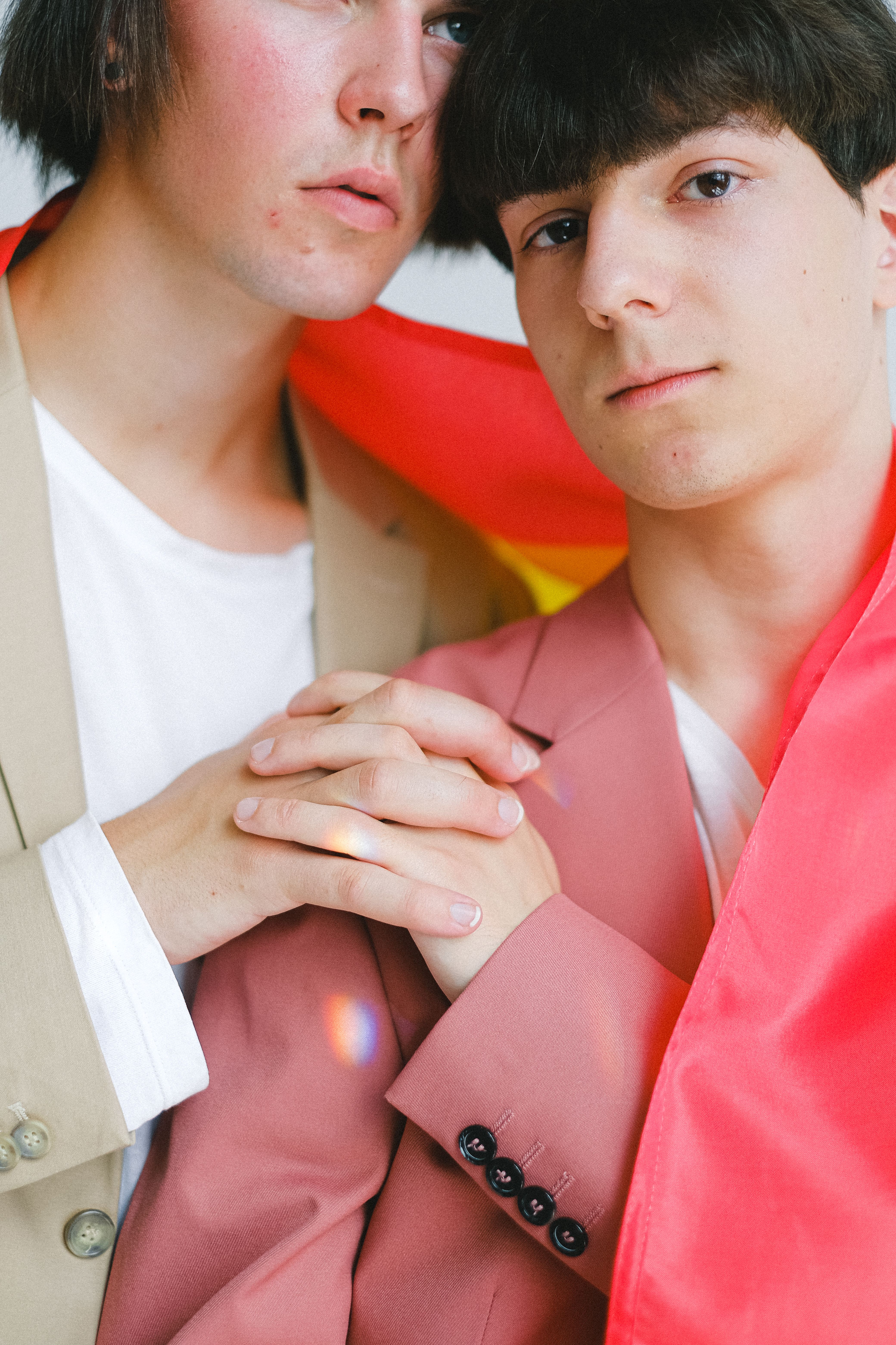 Portrait of a gay couple wrapped in a pride flag, expressing love and togetherness.