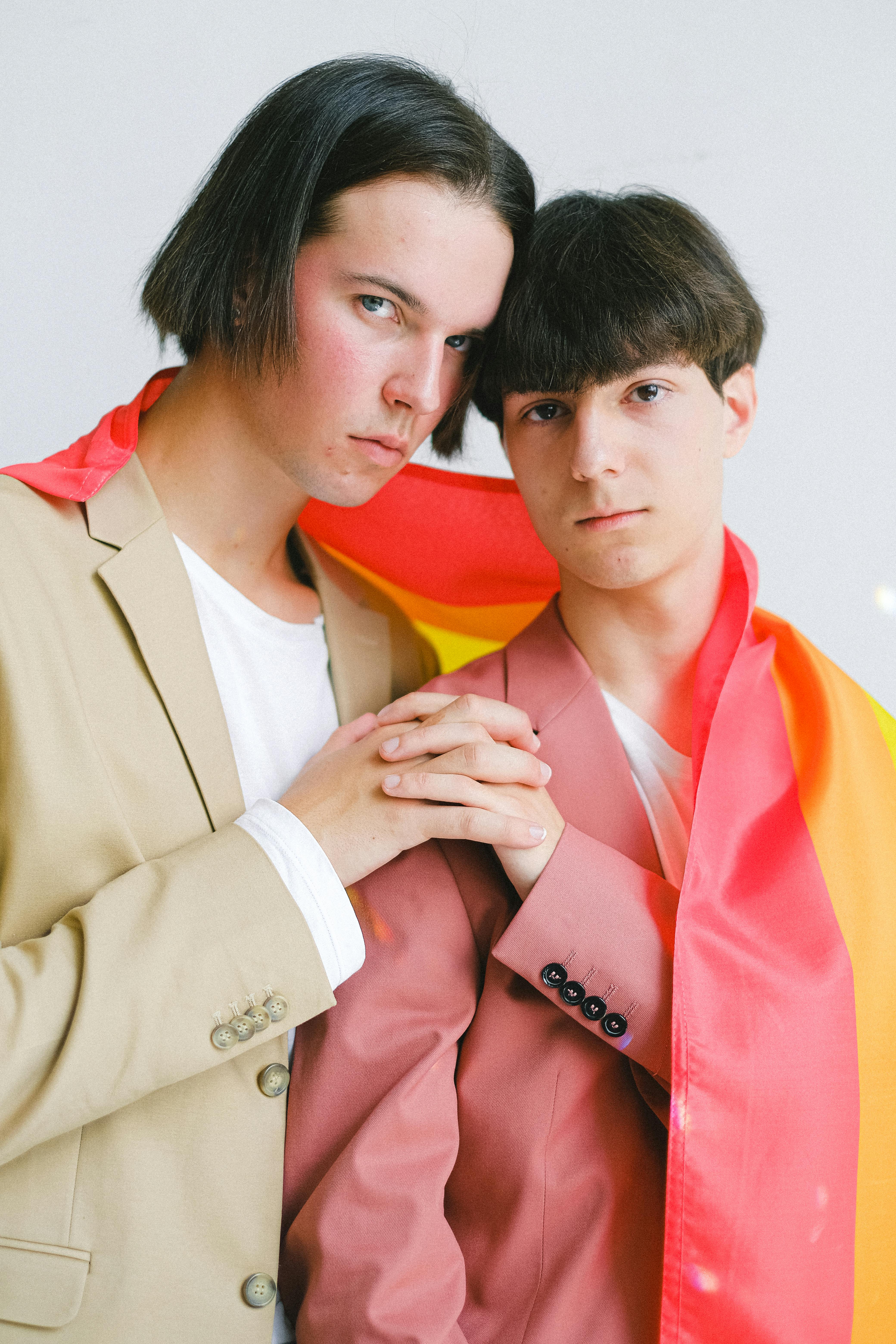 two men with a gay pride flag holding hands