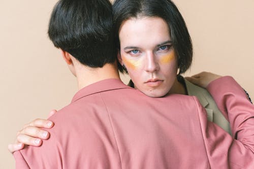 Man with Makeup Hugging A Man in Pink Suit