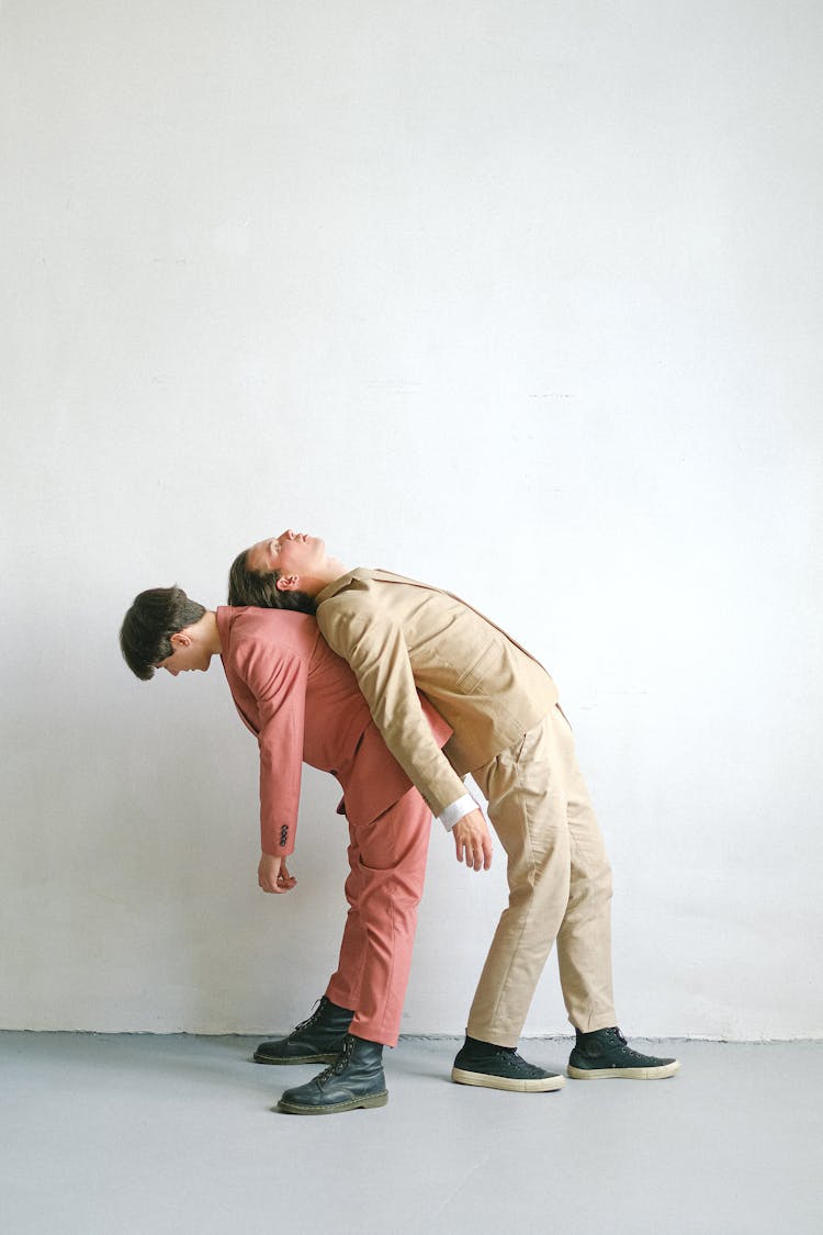 Man In Brown Suit Bending On Man In Pink Suit