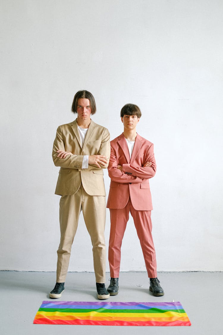 Two Men Standing Next To A Gay Pride Flag