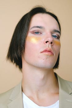 Close-up portrait of a young adult with gold eye makeup, showcasing contemporary fashion trends.