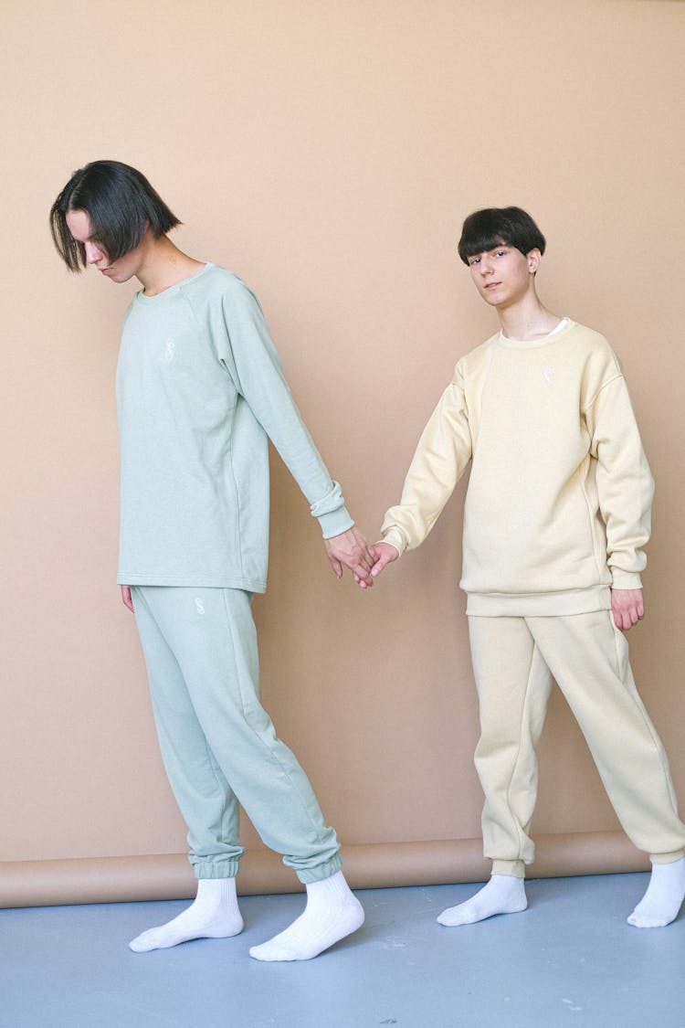 Two Men Holding Hands Wearing White And Blue Sweatshirts And Sweatpants