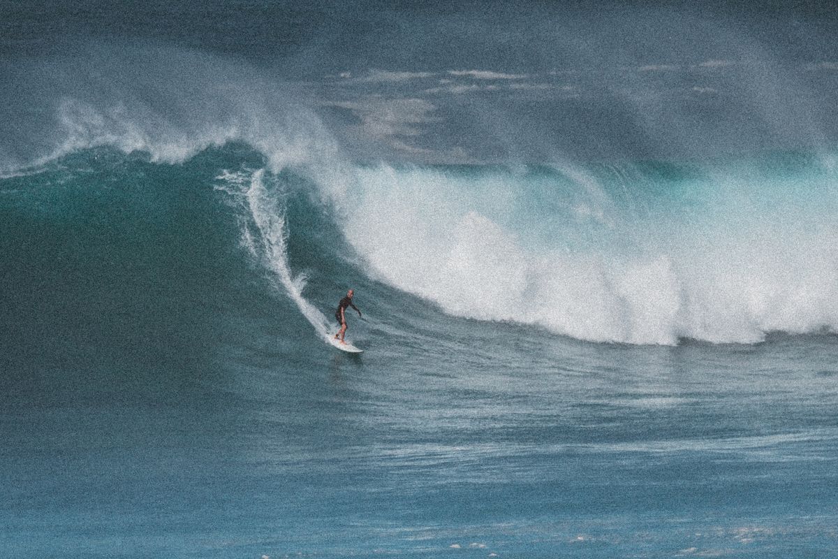 Professional surfer dropping into a giant barrel wave during a surf competition