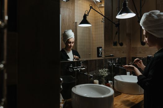 Woman engaging in beauty routine with face mask in a stylish bathroom setting. Self-care in process.