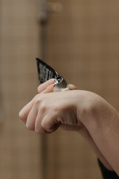 Close-up of hands applying cream from a tube in a bathroom. Perfect for skincare and beauty themes.