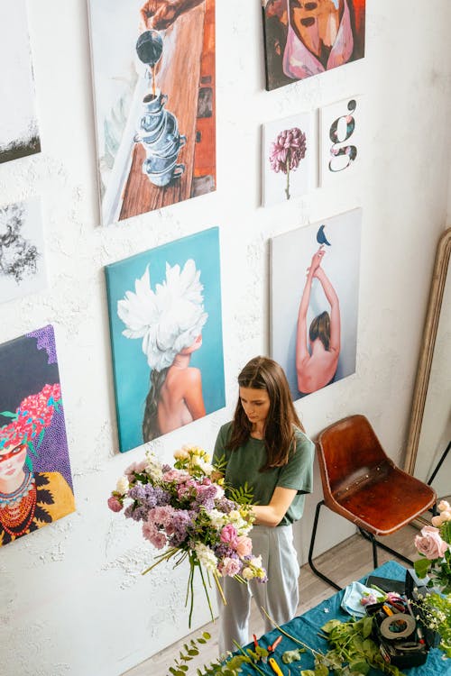 Woman Holding a Bouquet of Flowers Near Paintings