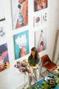 在一家艺术工作室里，一名妇女正在摆放一束鲜花，墙上挂着画作