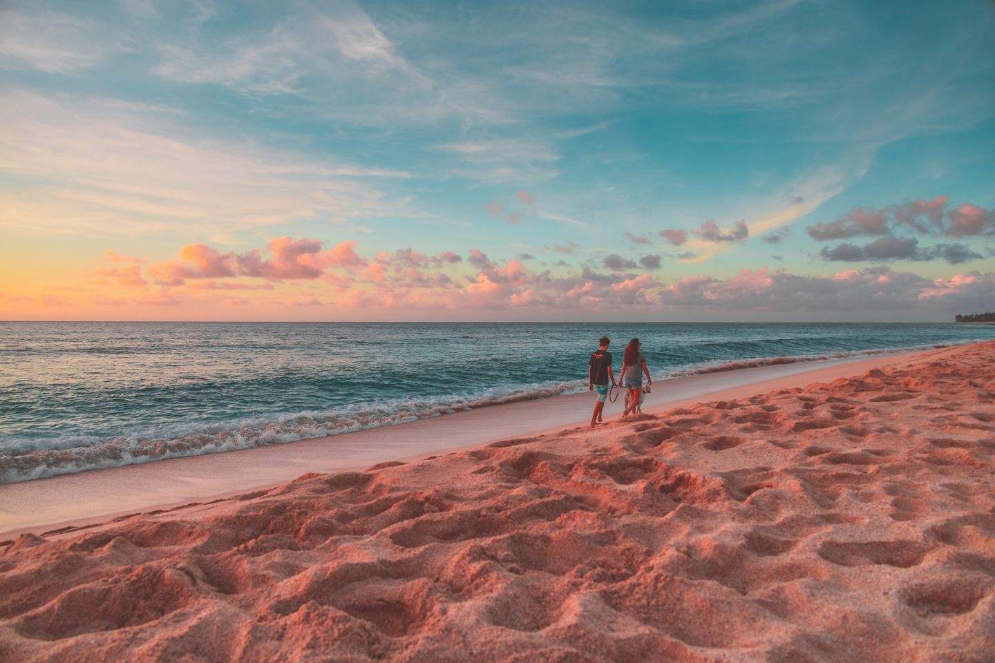 A couple walking a Hawaiian beach at sunset