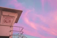 在粉红色的日落天空下，带有 “没有救生员当值” 标志的救生员塔