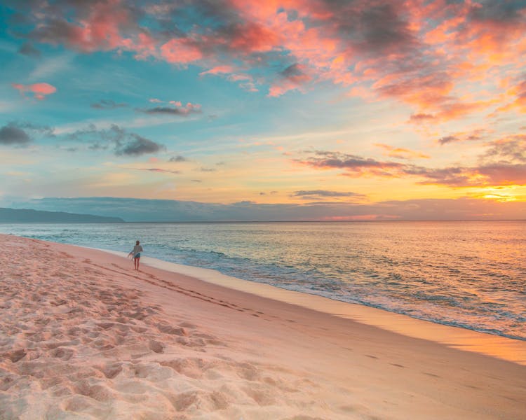 Person Walking On Beach During Sunset