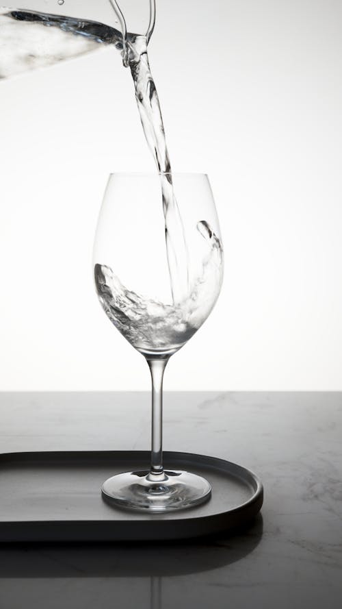 Water Being Poured into a Clear Wine Glass