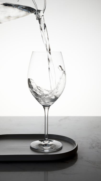 Free Water Being Poured into a Clear Wine Glass Stock Photo
