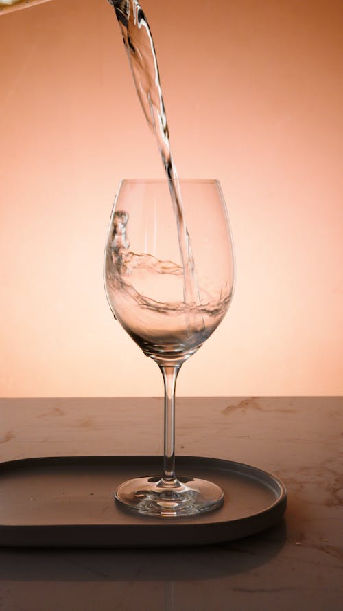 Water Being Poured into a Clear Wine Glass 