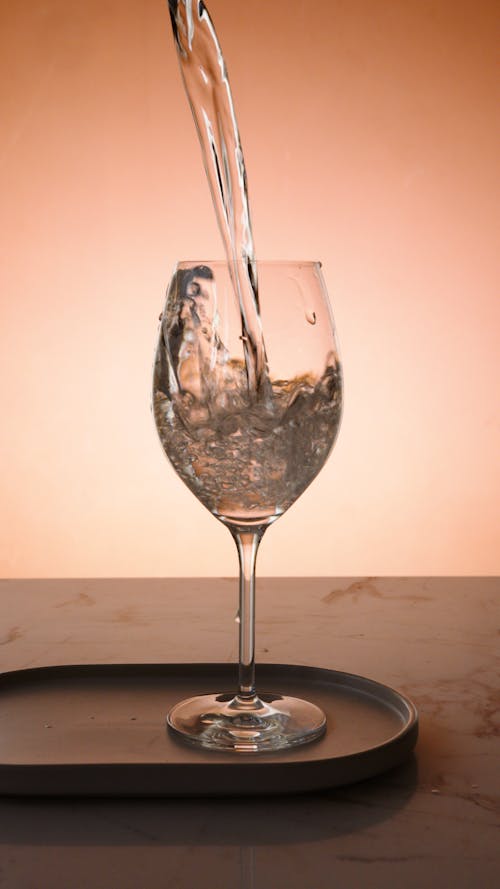 Water Being Poured into a Clear Wine Glass