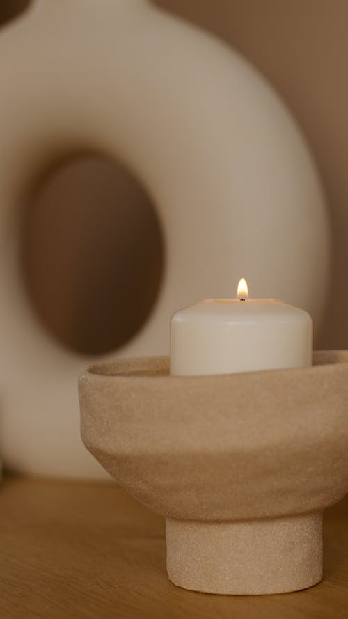 White Lighted Pillar Candle on Brown Wooden Holder