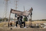 Full body side view of black male workers in elegant suits returned to native poor city and sitting in hut