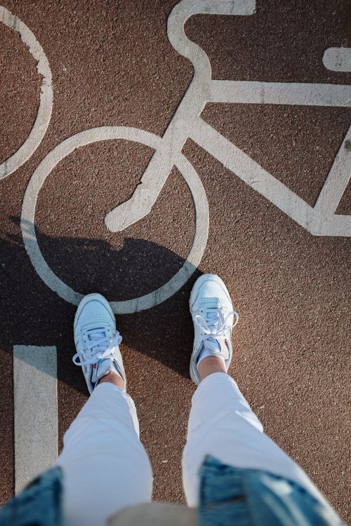 Free White sneakers on a bike lane with bicycle icon pavement markings, urban scene. Stock Photo