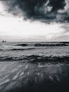 Free Black and white of wavy ocean near sandy coast under cloudy sky in stormy weather Stock Photo