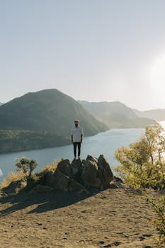 在阿根廷拉安戈斯图拉别墅，一名男子站在岩石上，背后是风景优美的山景和湖泊