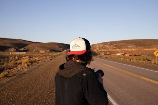 白天，一个人拿着相机站在阿根廷沙漠景观的道路上