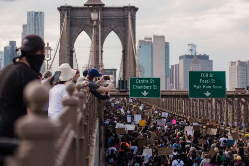 Free Massive protest on Brooklyn Bridge with city skyline in background, focusing on social justice. Stock Photo