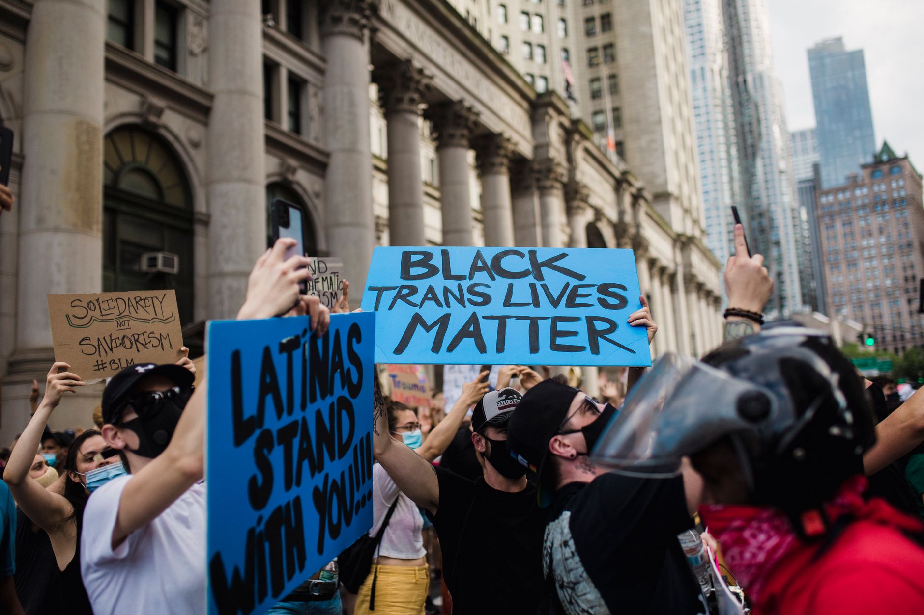 A vibrant city protest advocating for Black Trans rights with diverse participants holding signs.