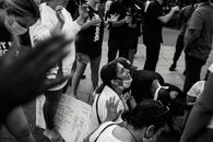 一群成年人在户外抗议中一同祈祷，展现了团结一致