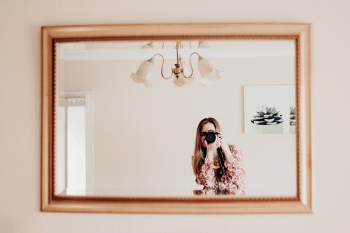 Free Woman Holding a Camera in Front of a Mirror Stock Photo