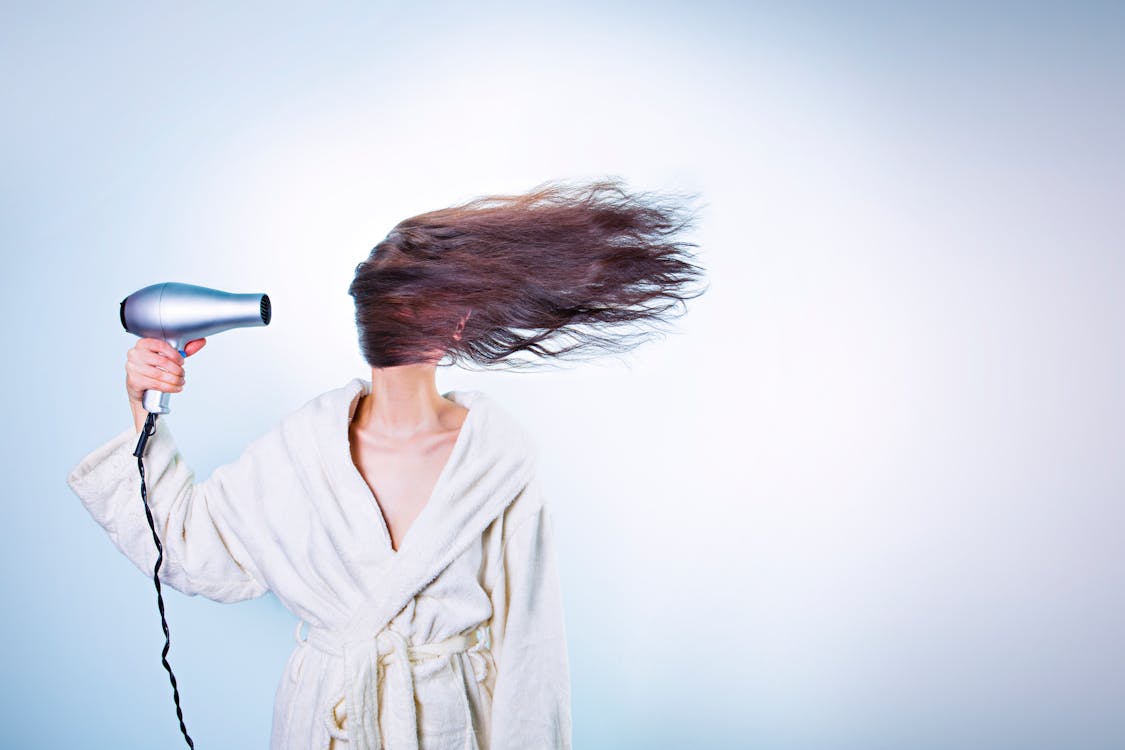 Woman Holding Gray Hair Dryer and Wearing White Bathrobe