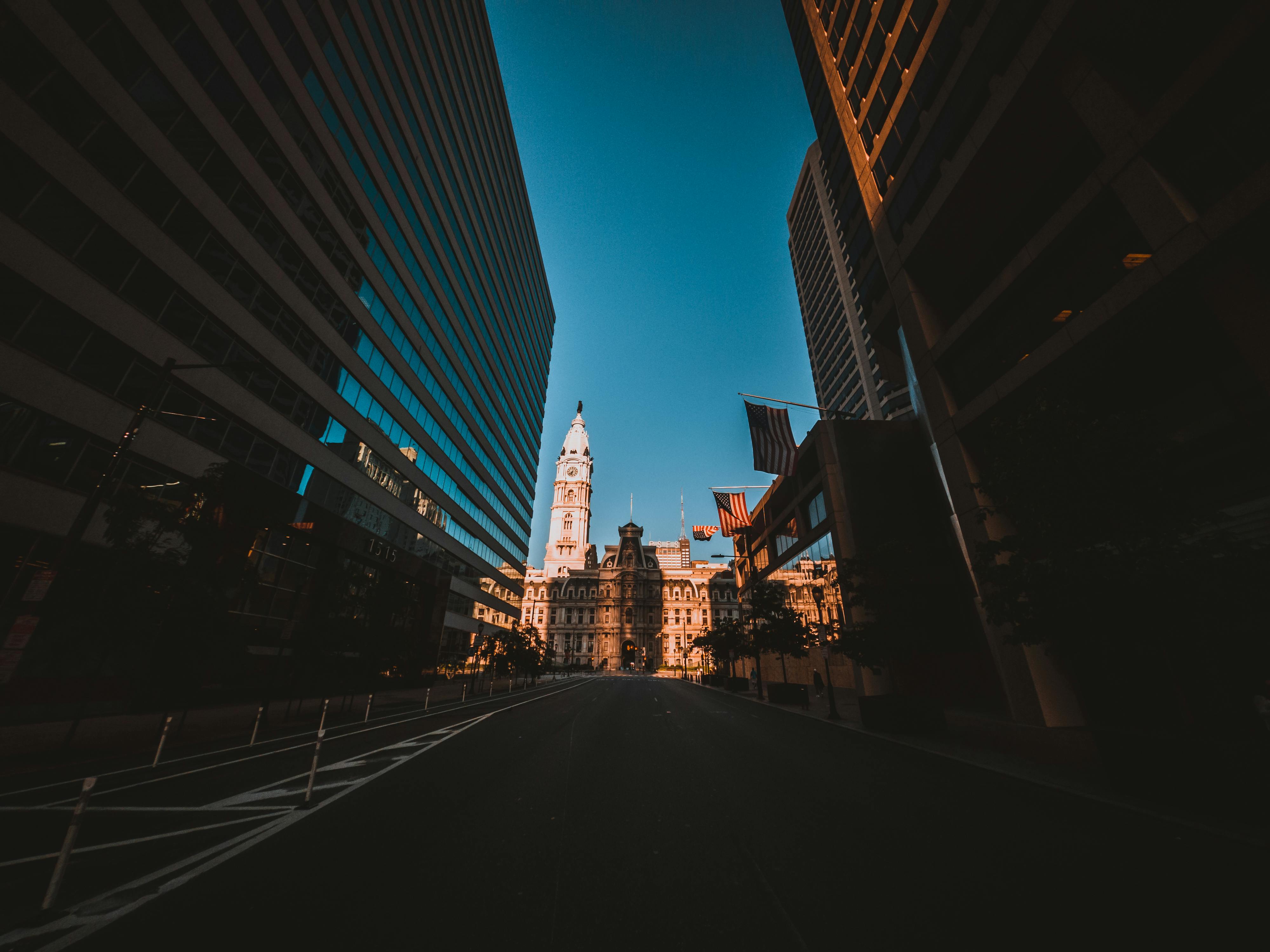 From below of aged house exterior and contemporary multistage buildings near road under blue sky in town in evening