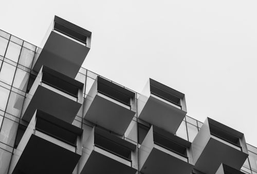 Free Grayscale photo of a modern building's glass facade in Melbourne, featuring geometric balconies. Stock Photo